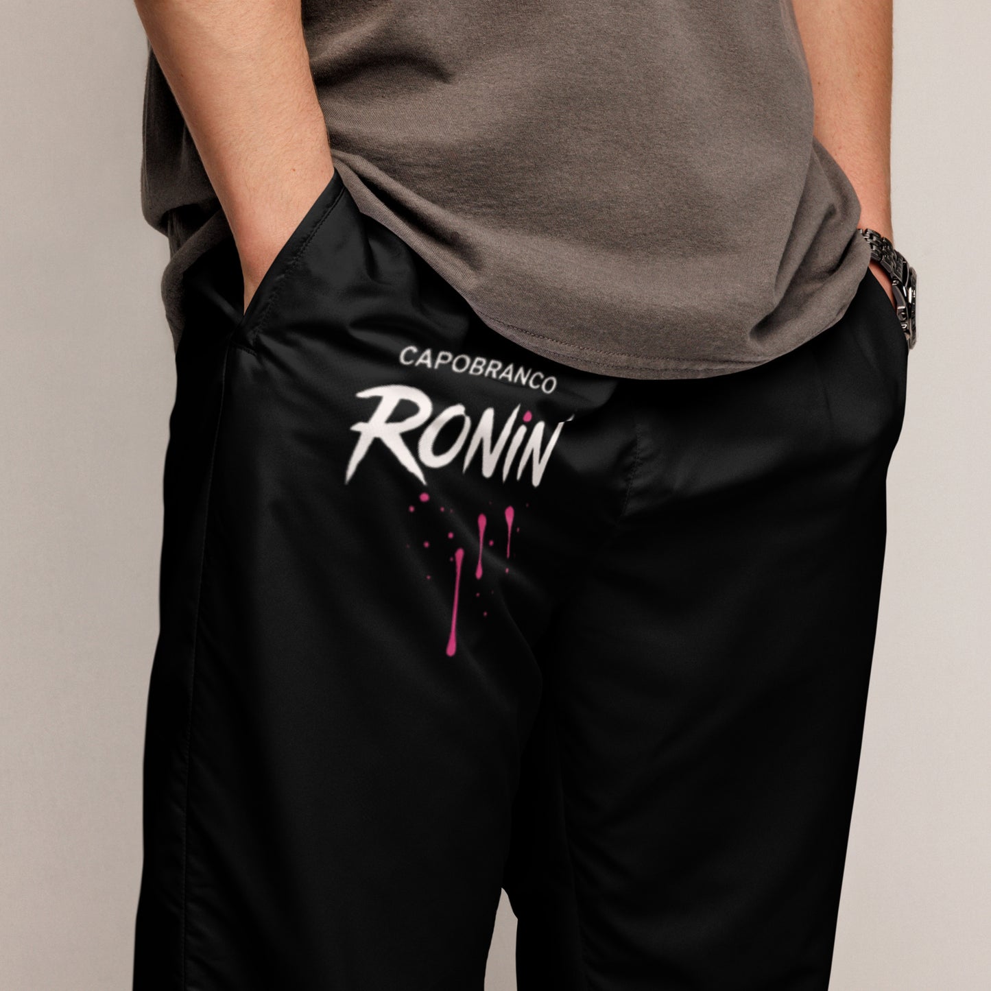 Close-up of Capobranco Ronin Neon joggers – black oversized streetwear pants with bold fuchsia Ronin print.